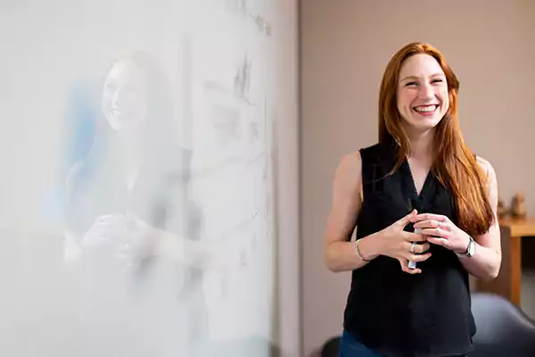  A professional stands by a whiteboard in a meeting room.